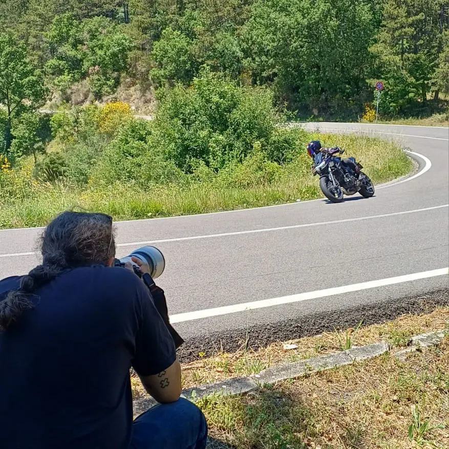 Emilio Latini mentre fotografa un motociclista in curva a Bocca Serriola per FotoMoto.Click